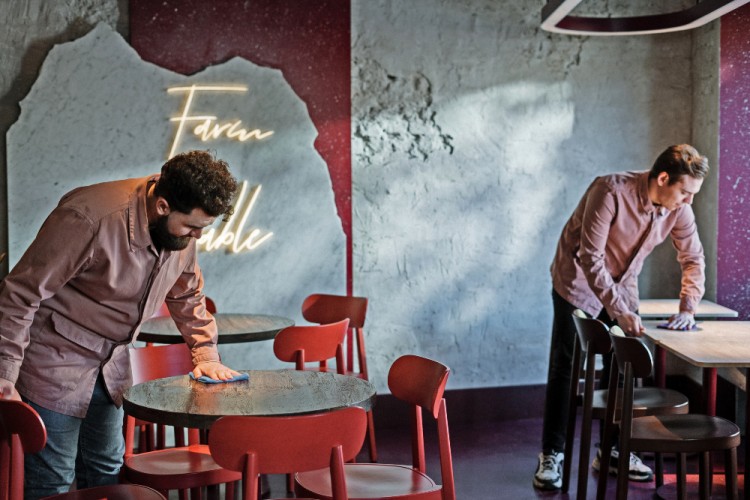 two young men cleaning tables at a coffee shop